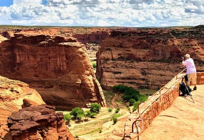 Man standing on rock formation against sky