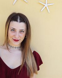 Portrait of smiling young woman standing against wall