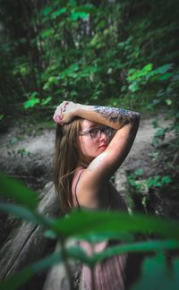 Woman standing by tree trunks in forest