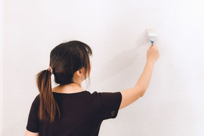 Rear view of woman standing against wall