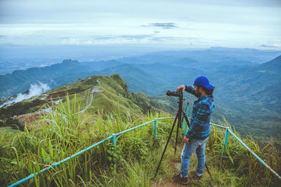 Man photographing on mountain against sky