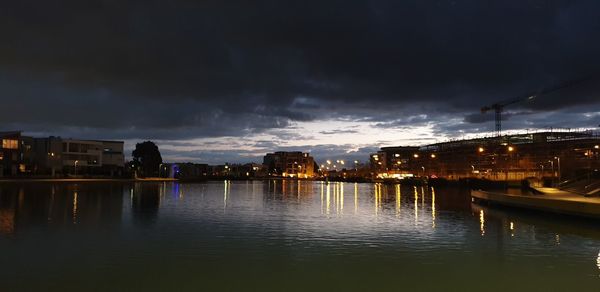 River by illuminated buildings against sky at night