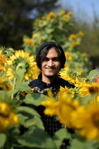 Portrait of smiling woman standing on yellow flowering plants