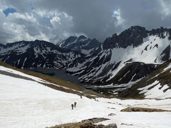 Scenic view of snowcapped mountains with hikers against sky