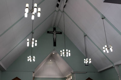 Low angle view of illuminated chandelier hanging on ceiling in building