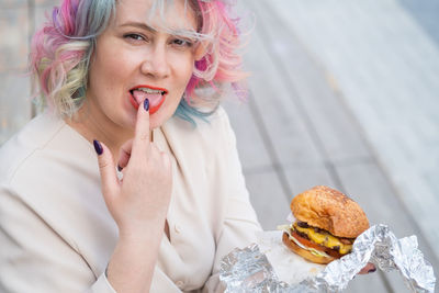 Woman licking finger holding burger