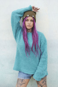 Portrait of a beautiful young woman standing against wall