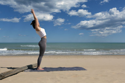 Young female athlete performing pilates at the seashore