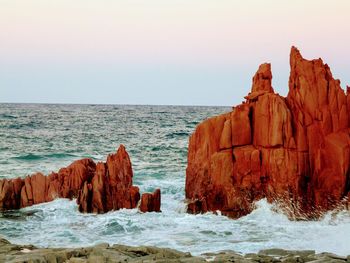 Rock formation in sea against clear sky