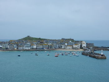 Sailboats in sea by city against sky