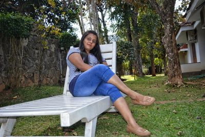 Portrait of woman sitting on lounge chair in yard