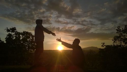 Silhouette people standing by tree against sky during sunset