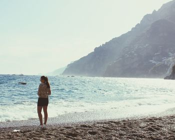 Rear view of woman standing at shore