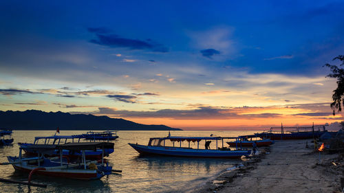 Boats moored in sea at sunset