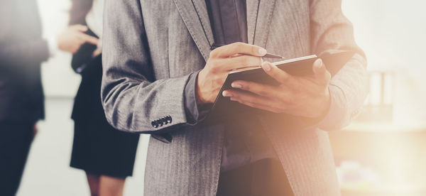 Midsection of businessman writing in book 