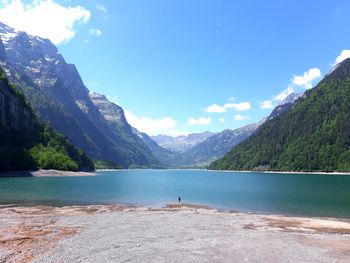 Scenic view of lake and mountains against blue sky