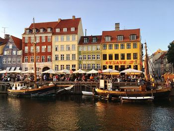 Boats moored in canal by buildings against clear sky