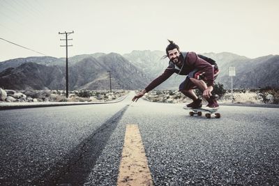 Man skateboarding on road against clear sky