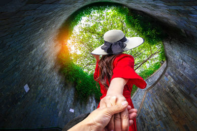 Woman wearing hat holding umbrella while standing outdoors