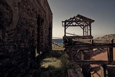 Old abandoned building by sea against sky