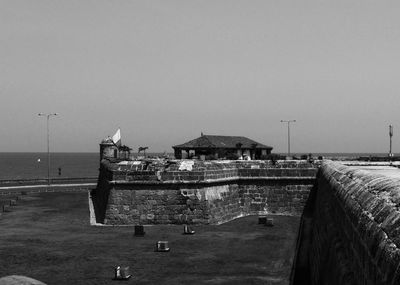 Buildings by sea against clear sky