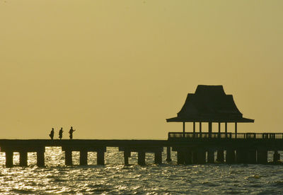 Silhouette pier over sea against clear sky during sunset