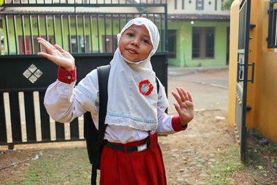 Portrait of girl in hijab standing against gate