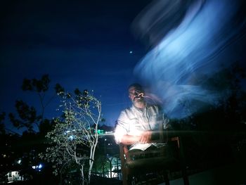 Digital composite image of man and illuminated lighting equipment against sky at night