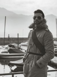 Handsome young man in winter coat standing at lakeshore