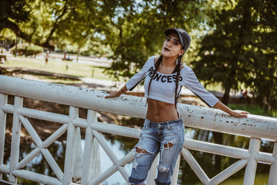 Portrait of young woman standing against railing