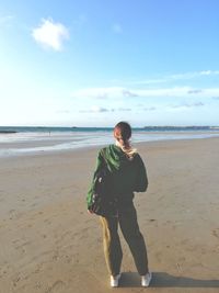 Rear view of woman on beach against sky