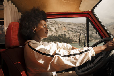 Thoughtful young woman driving van during road trip