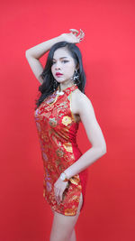 Portrait of woman standing against red background