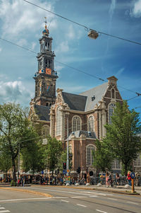 Street with old church steeple and blue sky in amsterdam. the netherland capital full of canals.