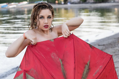 Portrait of seductive woman holding umbrella at beach