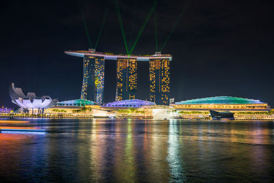 Illuminated building by river at night