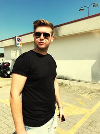 Portrait of young man wearing sunglasses standing against sky