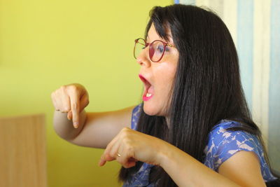 Portrait of woman with arms hair against wall