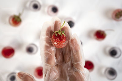 Hand in protective glove holds frozen strawberry in ice cube. homemade food. top view.