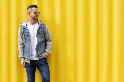 Portrait of a young cool man over yellow background.