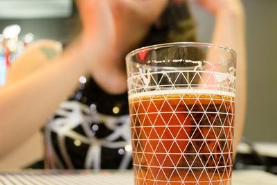 Close-up of hand holding drink glass on table