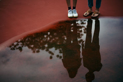 Low section of friends standing by puddle