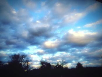 Low angle view of silhouette trees against cloudy sky