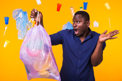 Young man standing against yellow wall