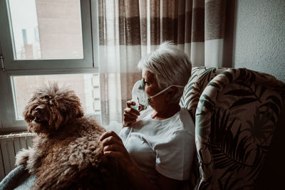 Rear view of woman with dog sitting at home