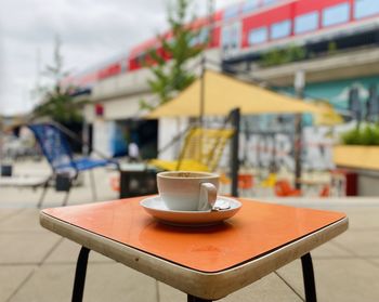 Coffee cup on table in cafe against building