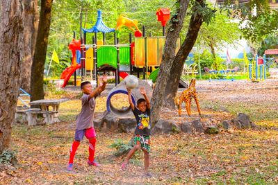 Full length of children playing with plants in park