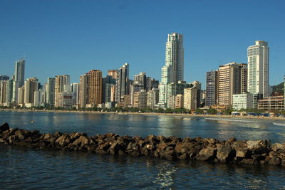 Sea by cityscape against clear sky