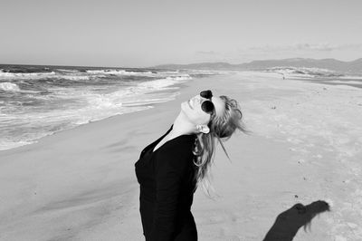 Rear view of man on beach against sky