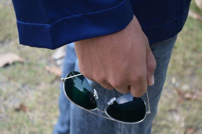 High angle view of man holding sunglasses while standing on land